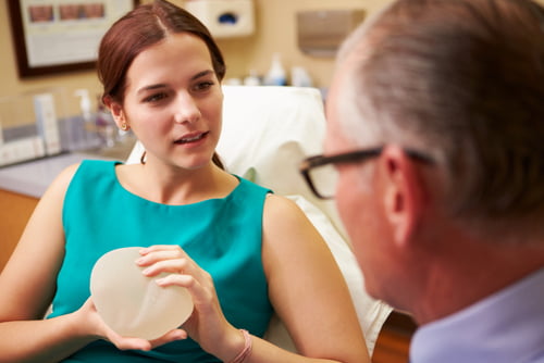 Woman holding breast implants in consultation with cosmetic breast surgeon