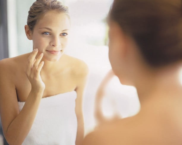 Woman examines skin in mirror