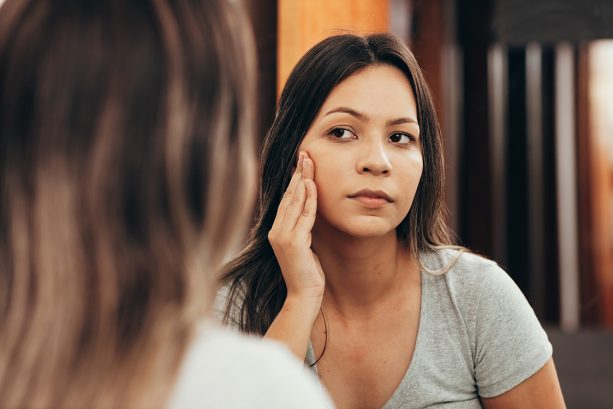 Woman looking at her skin in the mirror