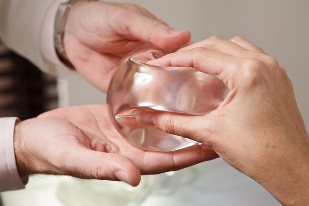 Woman holding breast implant while discussing with surgeon