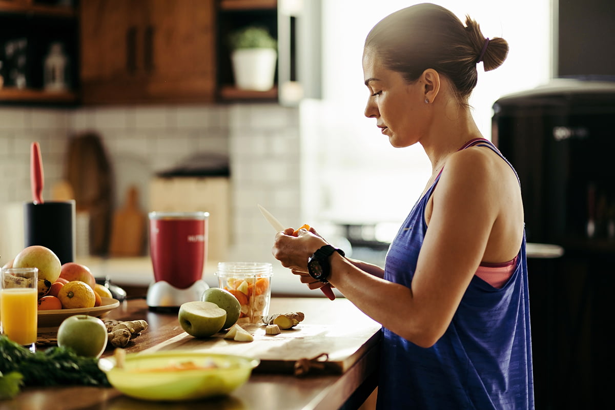 woman cutting fruit at the kitchen counter