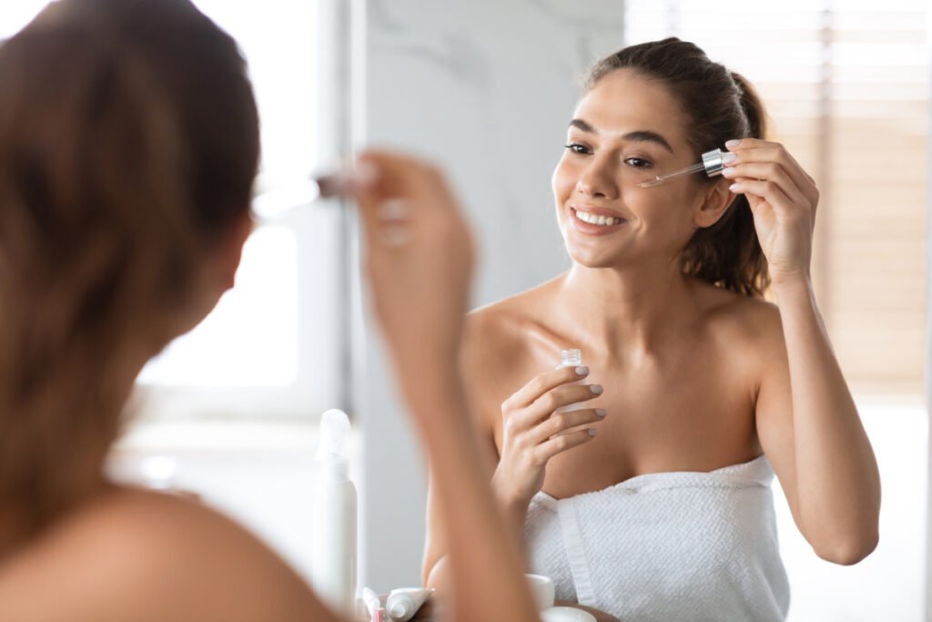 Young woman putting on retinoid as part of skincare routine